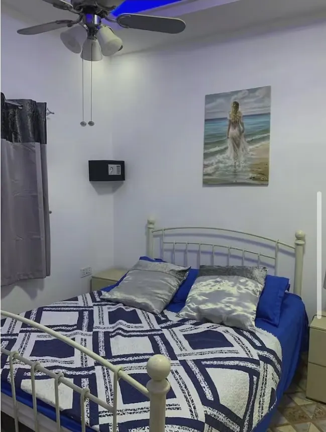 Bedroom 3: white metal bed with blue geometric quilt